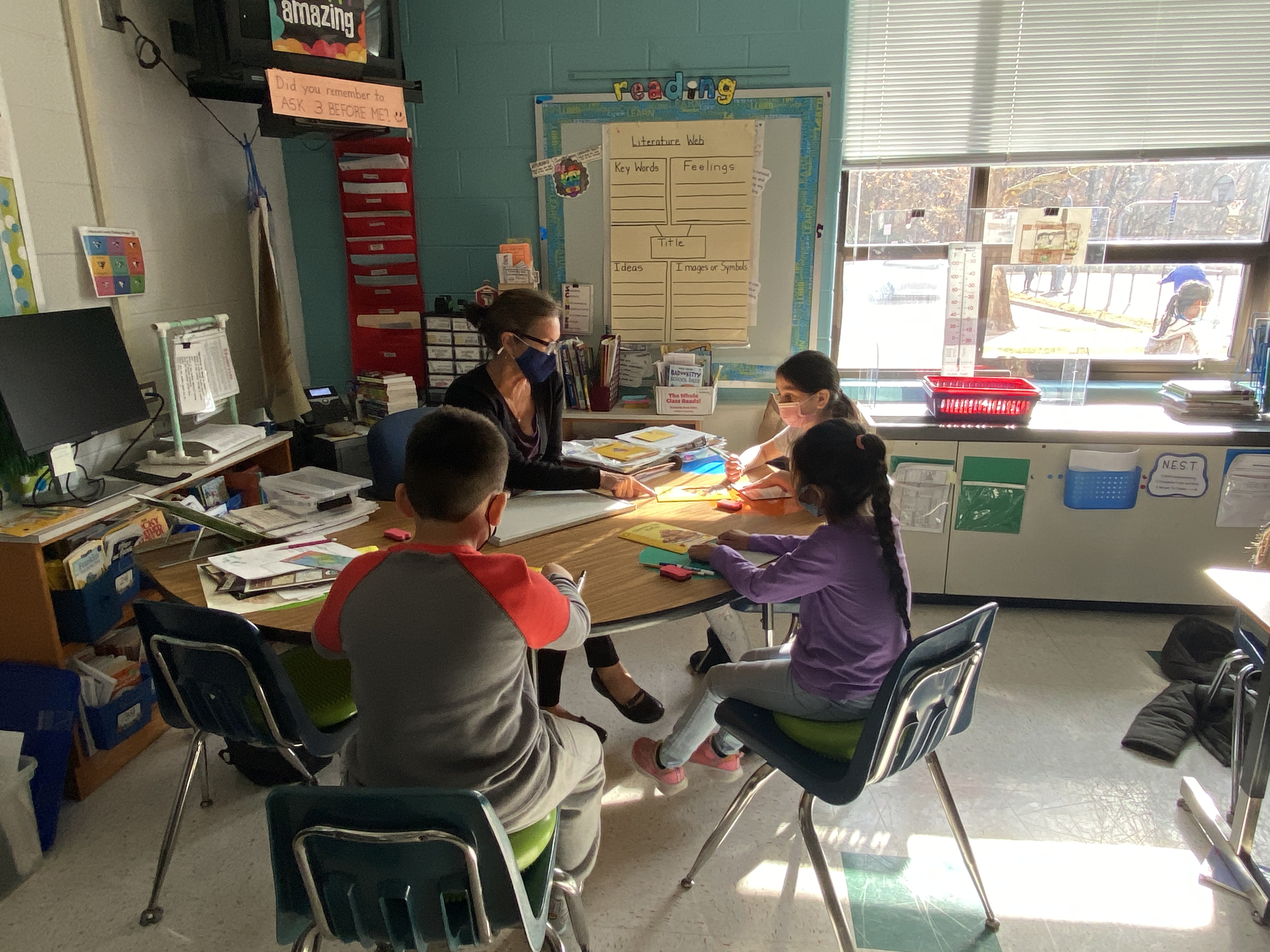 students at the table with teacher and books