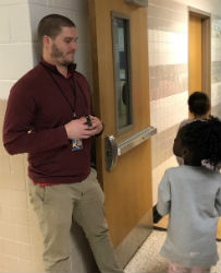 Mr williams standing by the gym door talking to a student