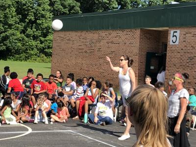 photo of teacher serving volleyball in game outside