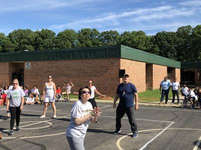 photo of teachers standing outside on blacktop playing volleyball