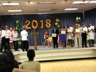 photo of students standing on stage with certificates in hand