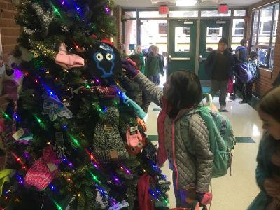 photo of student adding a mitten and hat to giving tree